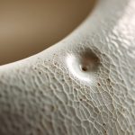 Macro close-up of a B-grade bone china piece showing a subtle pinhole flaw.