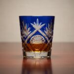 Exquisite Edo Kiriko whisky glass with amber liquid reflecting light.